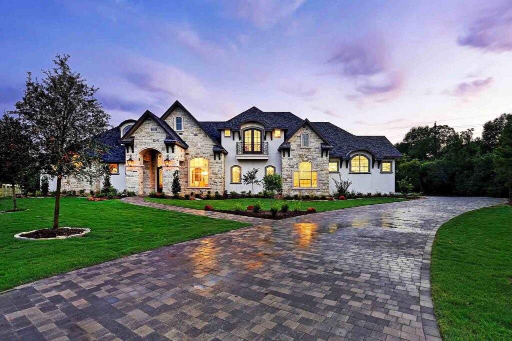 Stone estate with curved driveway at dusk
