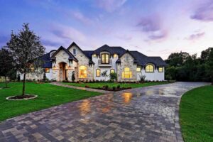 Stone estate with curved driveway at dusk