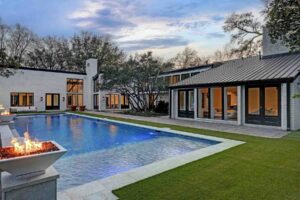 Luxury home exterior with pool and fire feature at dusk
