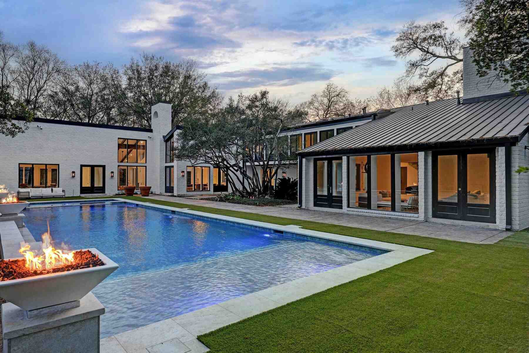 Luxury home exterior with pool and fire feature at dusk