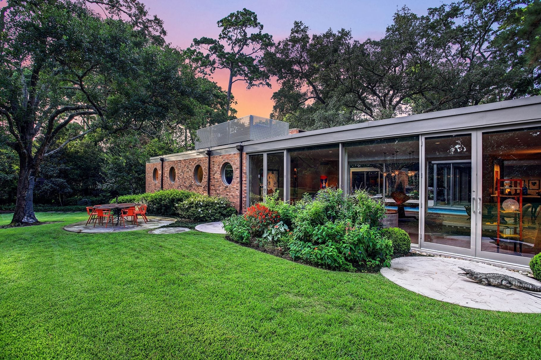 Modern home exterior with landscaped backyard at dusk