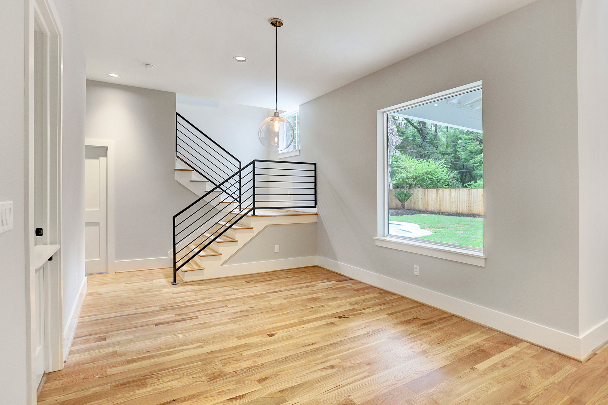 Empty modern interior with hardwood floors and black stair railing